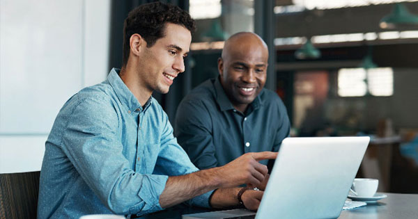 Deux personnes discutent devant un ordinateur portable en réunion