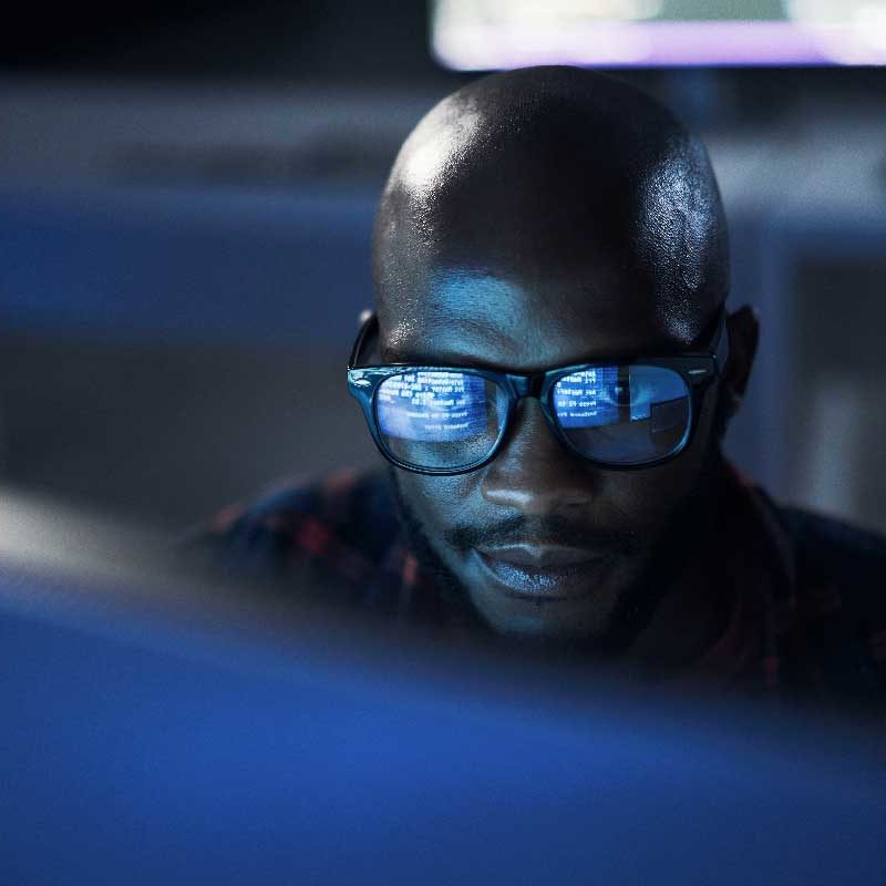Développeur travaillant la nuit, reflet d’écran dans ses lunettes